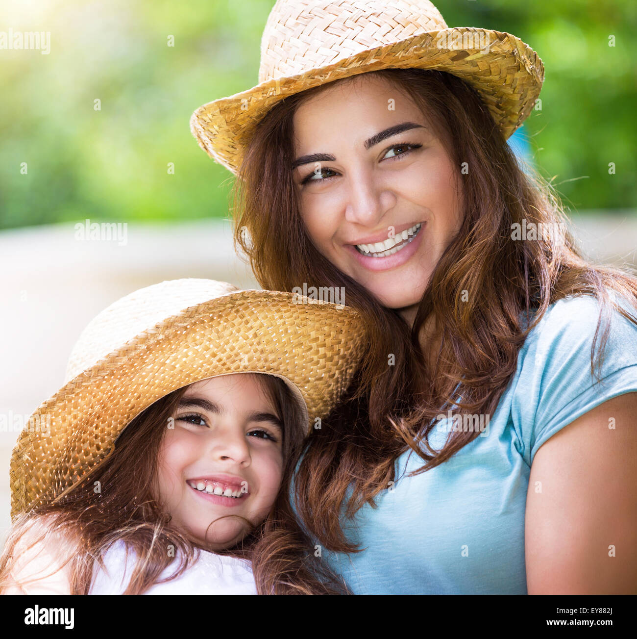 Portrait de famille heureuse à l'extérieur, jolie mère joyeuse avec petite fille portant des chapeaux de paille identiques et s'amuser Banque D'Images