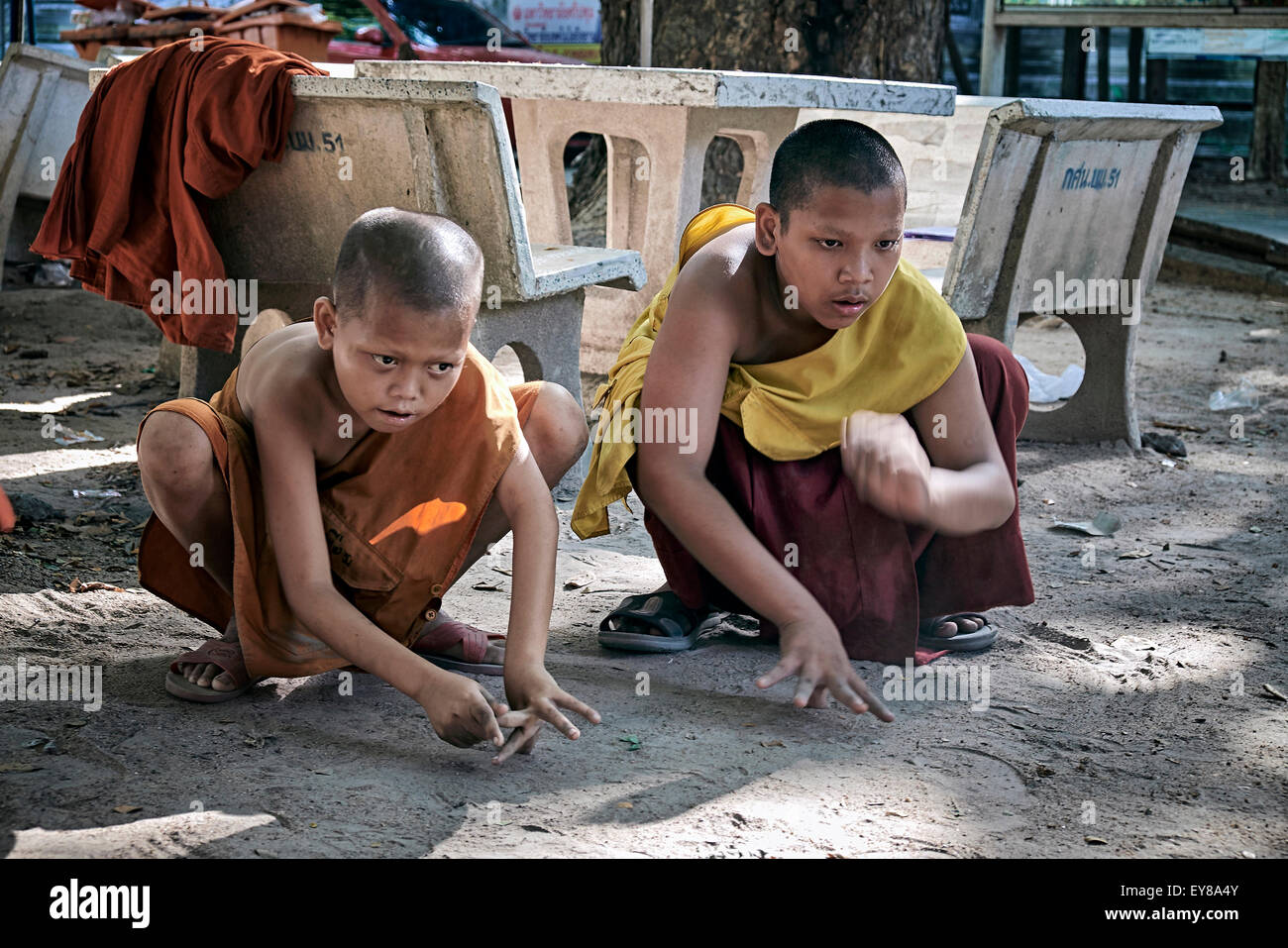 Jouer à des marbres. Jeune garçon moines bouddhistes jouant le jeu traditionnel de marbres. Thaïlande S. E. Asie Banque D'Images