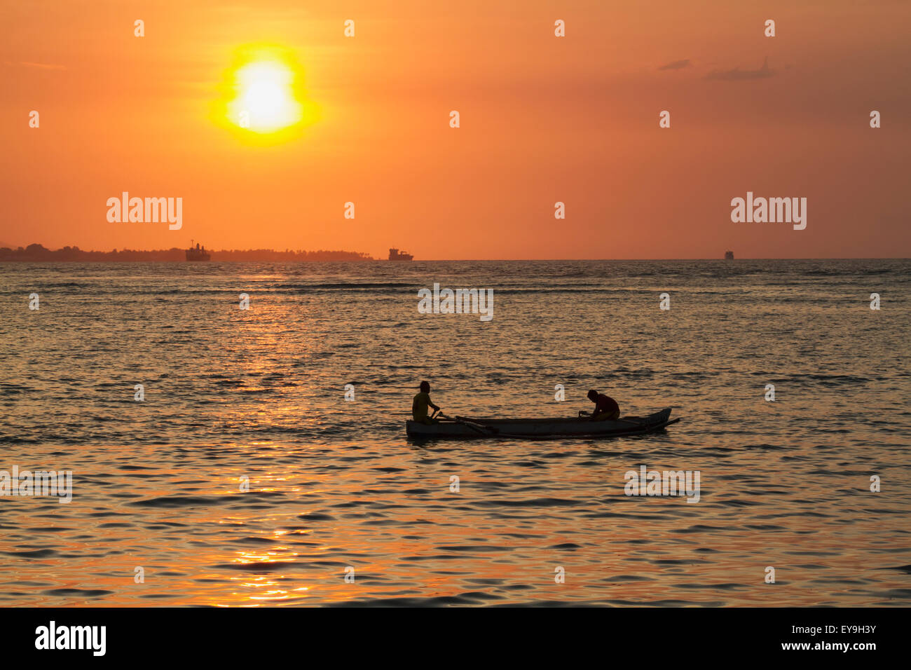 Hommes dans un bateau au coucher du soleil ; à Dili, au Timor oriental Banque D'Images