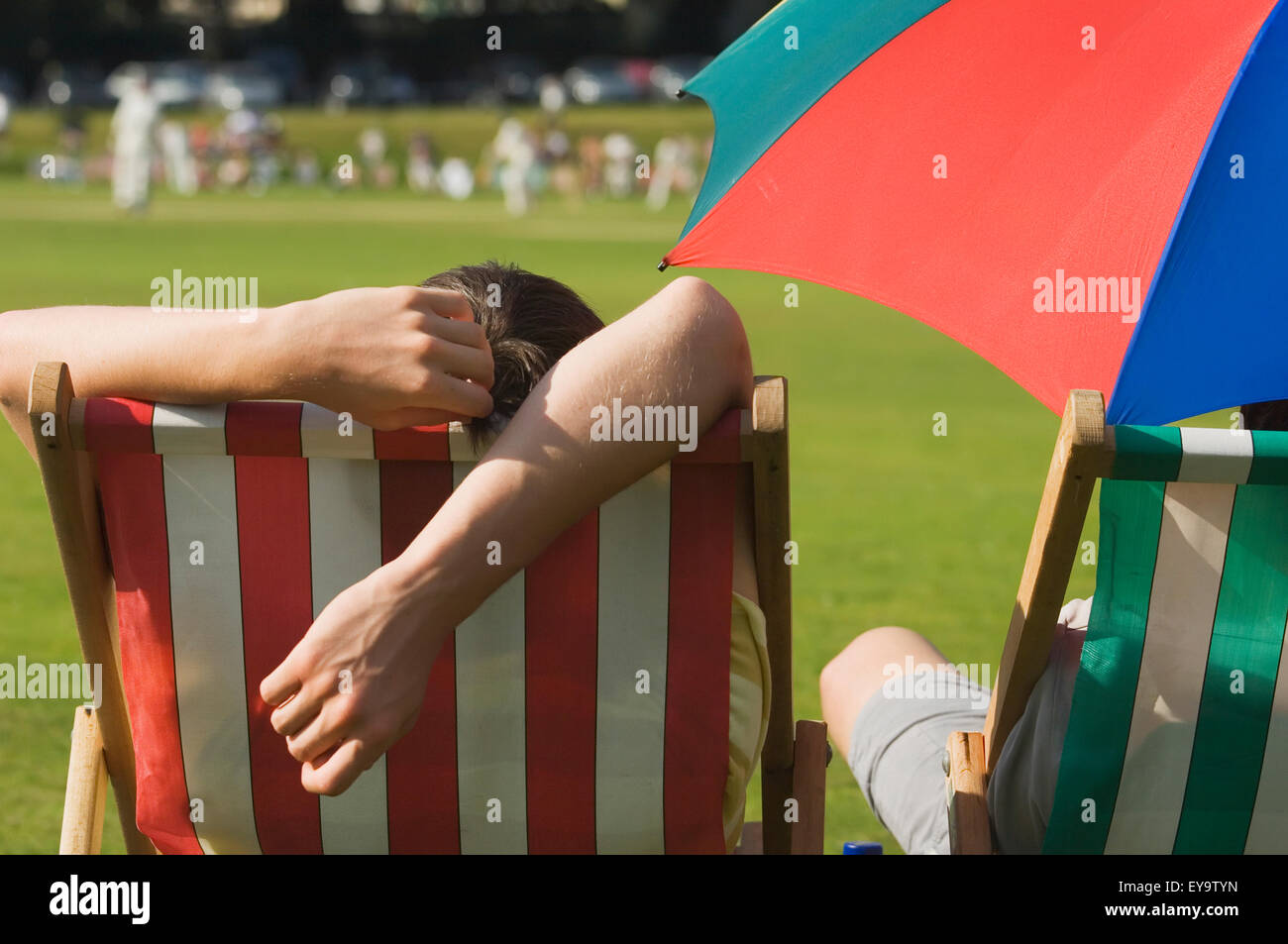 Vue arrière des spectateurs dans des chaises à regarder un match de cricket sur une chaude journée d'été à Hastings. Banque D'Images