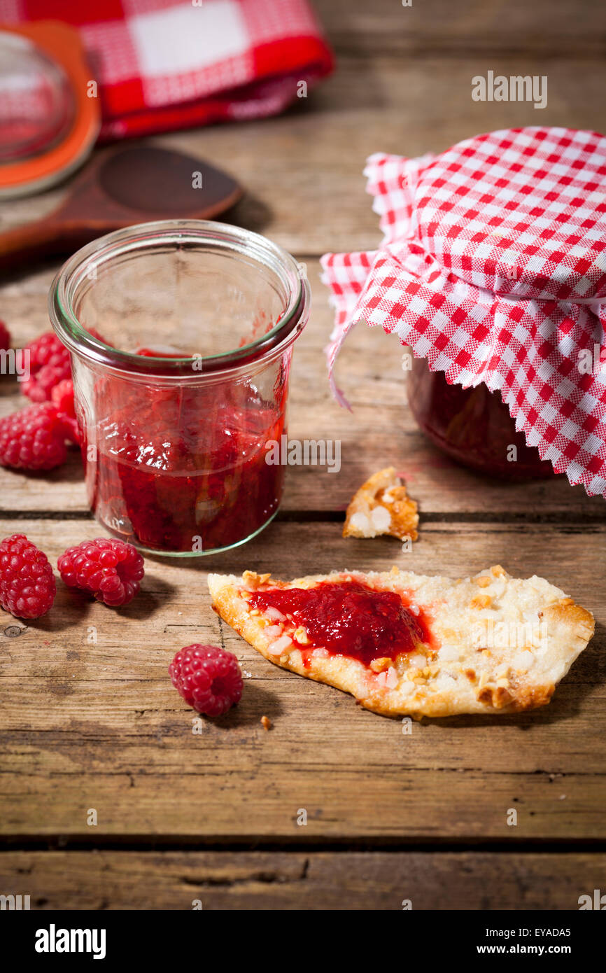Confiture de framboises à la main dans des bocaux sur table en bois, baies et errants cookie aux amandes, vertical Banque D'Images