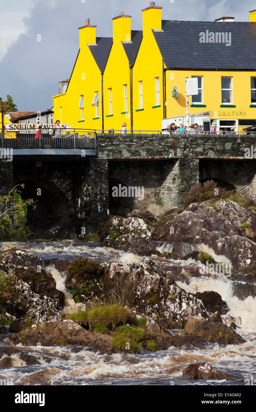 Bâtiment de couleur jaune vif et des piétons sur le pont ; de Sneem, le comté de Kerry, Irlande Banque D'Images