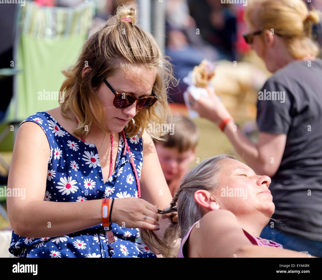 Charlton Park, Wiltshire, Royaume-Uni. Le 25 juillet, 2015. À l'atmosphère (WOMAD World of Music, Arts and Dance) Festival à Charlton Park le 25/07/2015 à Charlton Park, Malmesbury. Détente au soleil une longue femme tresses les cheveux d'une autre. Photo par Julie Edwards/Alamy Live News Banque D'Images Charlton Park, Wiltshire, Royaume-Uni. Le 25 juillet, 2015. À l'atmosphère (WOMAD World of Music, Arts and Dance) Festival à Charlton Park le 25/07/2015 à Charlton Park, Malmesbury. Détente au soleil une longue femme tresses les cheveux d'une autre. Photo par Julie Edwards/Alamy Live News Banque D'Images