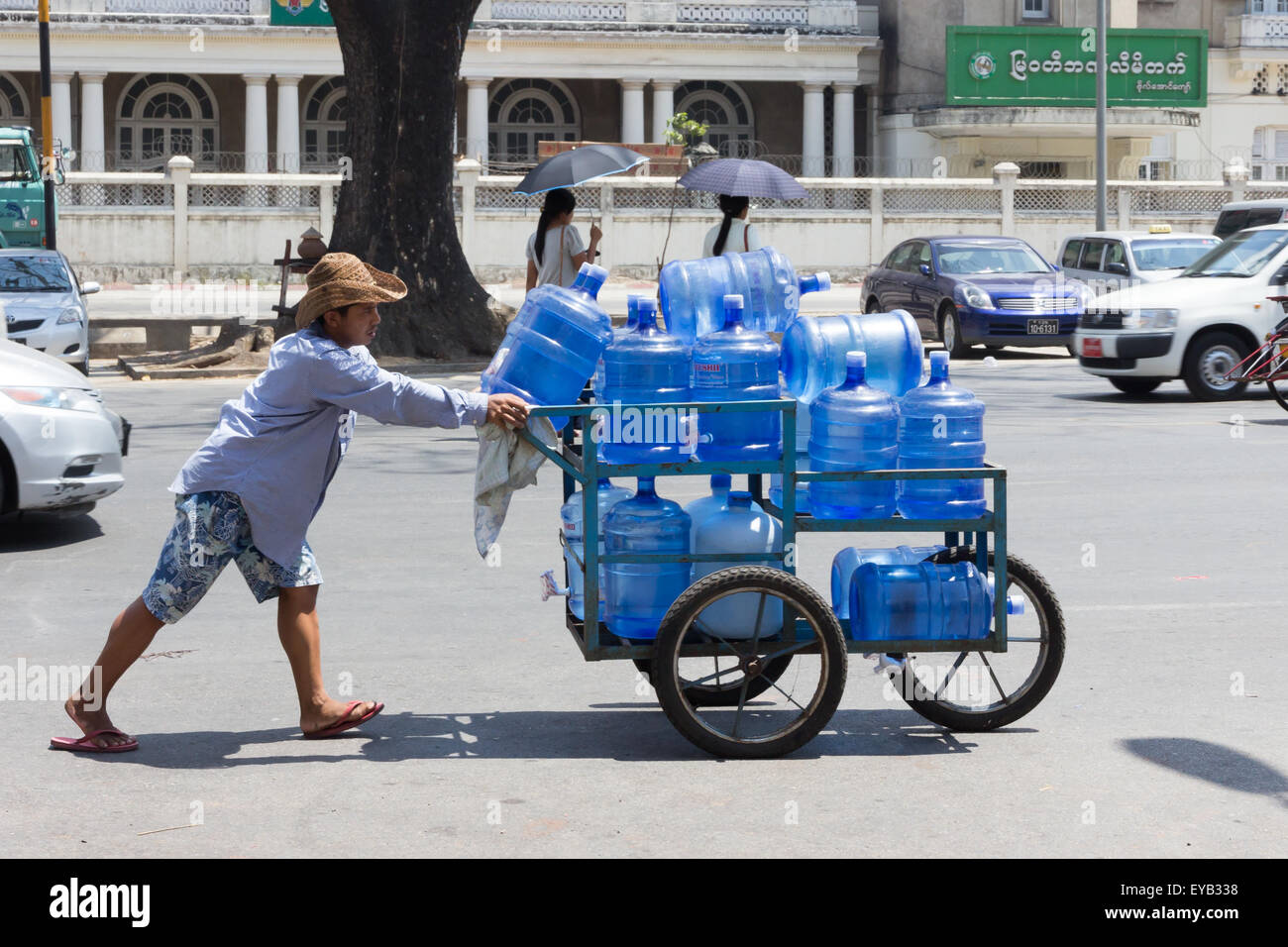 Yangon, Myanmar-May 8e 2014 : un homme pousse un chariot chargé avec des bouteilles d'eau. Les livraisons sont toujours effectuées de cette façon. Banque D'Images