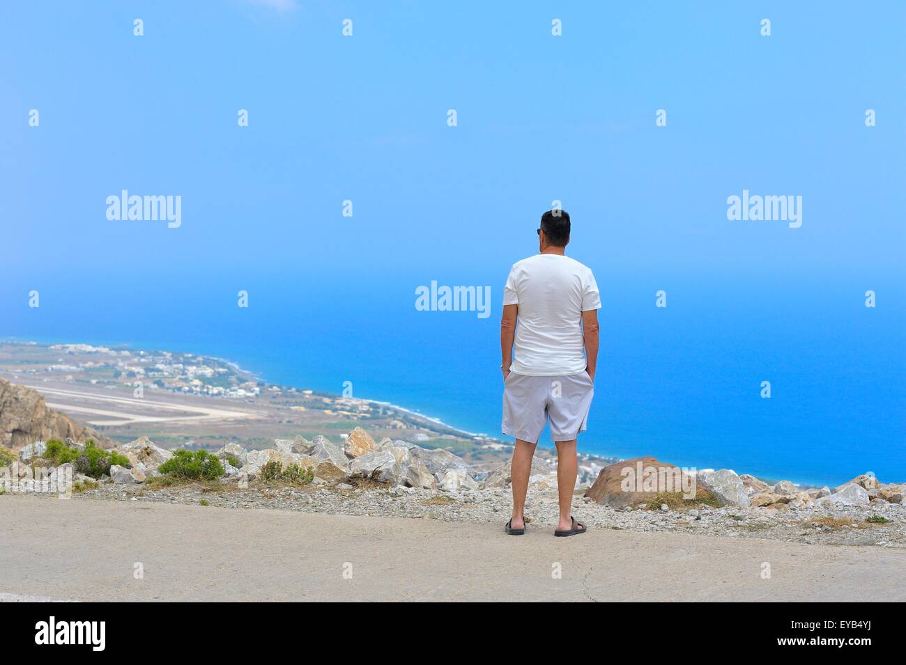 Un homme vu de messa vouno mountain le site de l'ancienne Thira, Santorin, Grèce. Avec l'aéroport et la mer en arrière-plan Banque D'Images