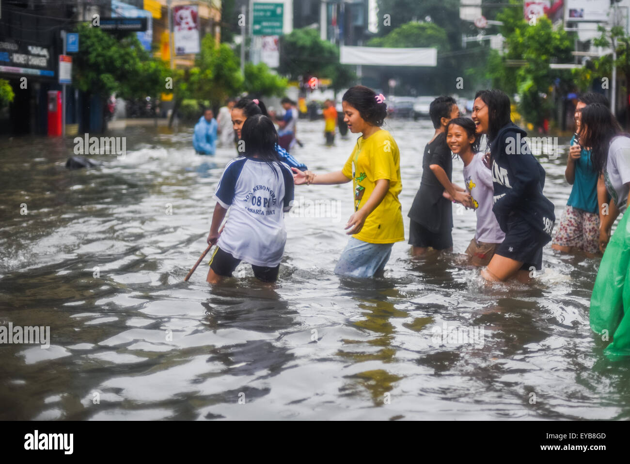 Les adolescents traversant la rue inondée avec excitation. Banque D'Images
