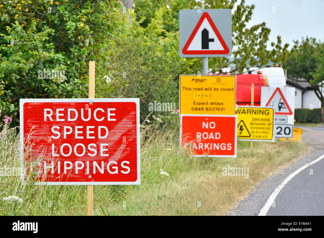 Les panneaux de signalisation routière de surchasse sont placés en file d'attente pour avertir de la sécurité et des perturbations par des travaux de resurfaçage de grainage sur la voie de campagne dans l'Essex, en Angleterre, au Royaume-Uni Banque D'Images