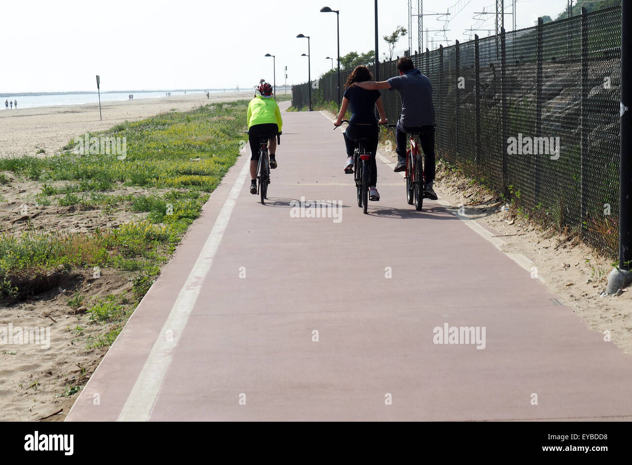 Randonnée cycliste et un couple comme ils le cycle sur une piste cyclable sur la plage. Banque D'Images