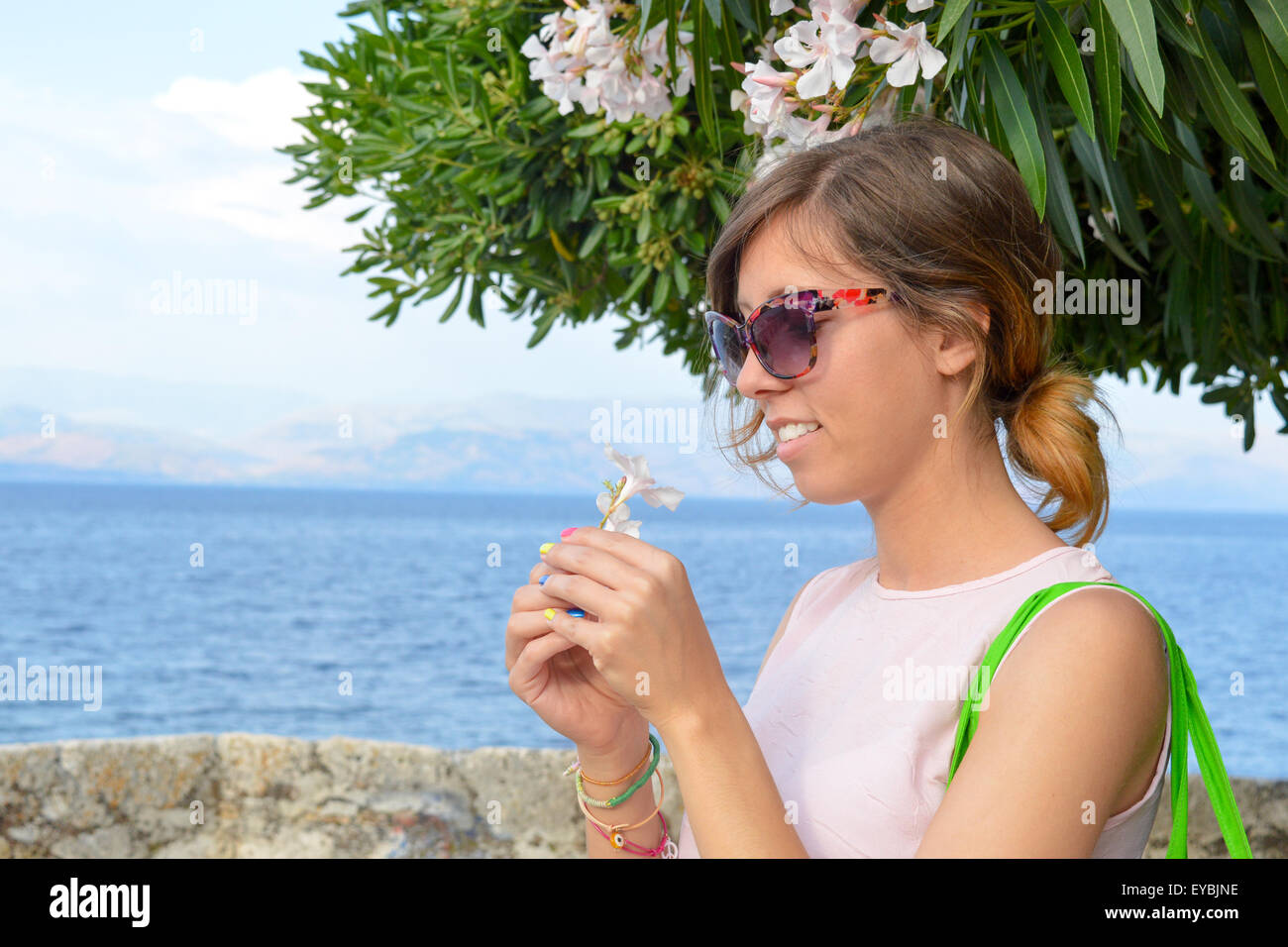 Jeune fille avec des lunettes tenant une fleur blanche dans sa main à la mer Banque D'Images