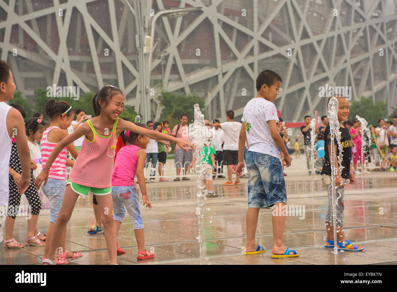 Les enfants chinois jouant parmi les têtes d'eau devant le nid d'Oiseau Stadium à Pékin, Juillet 2015 Banque D'Images