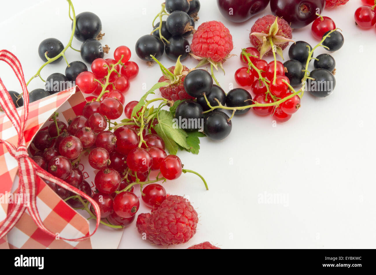 Fruits rouges colorés qui tombe hors de la boîte décoré sur fond blanc Banque D'Images