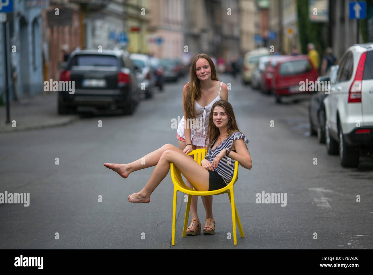 Deux jeunes filles petite amie. Photo conceptuelle, une fille de l'adolescence est assis sur une chaise au milieu de la rue, son ami se tient derrière Banque D'Images
