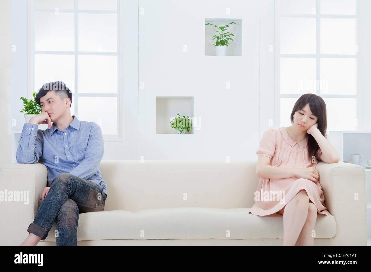 Jeune homme et femme enceinte assise sur le canapé avec mauvaise humeur, Banque D'Images