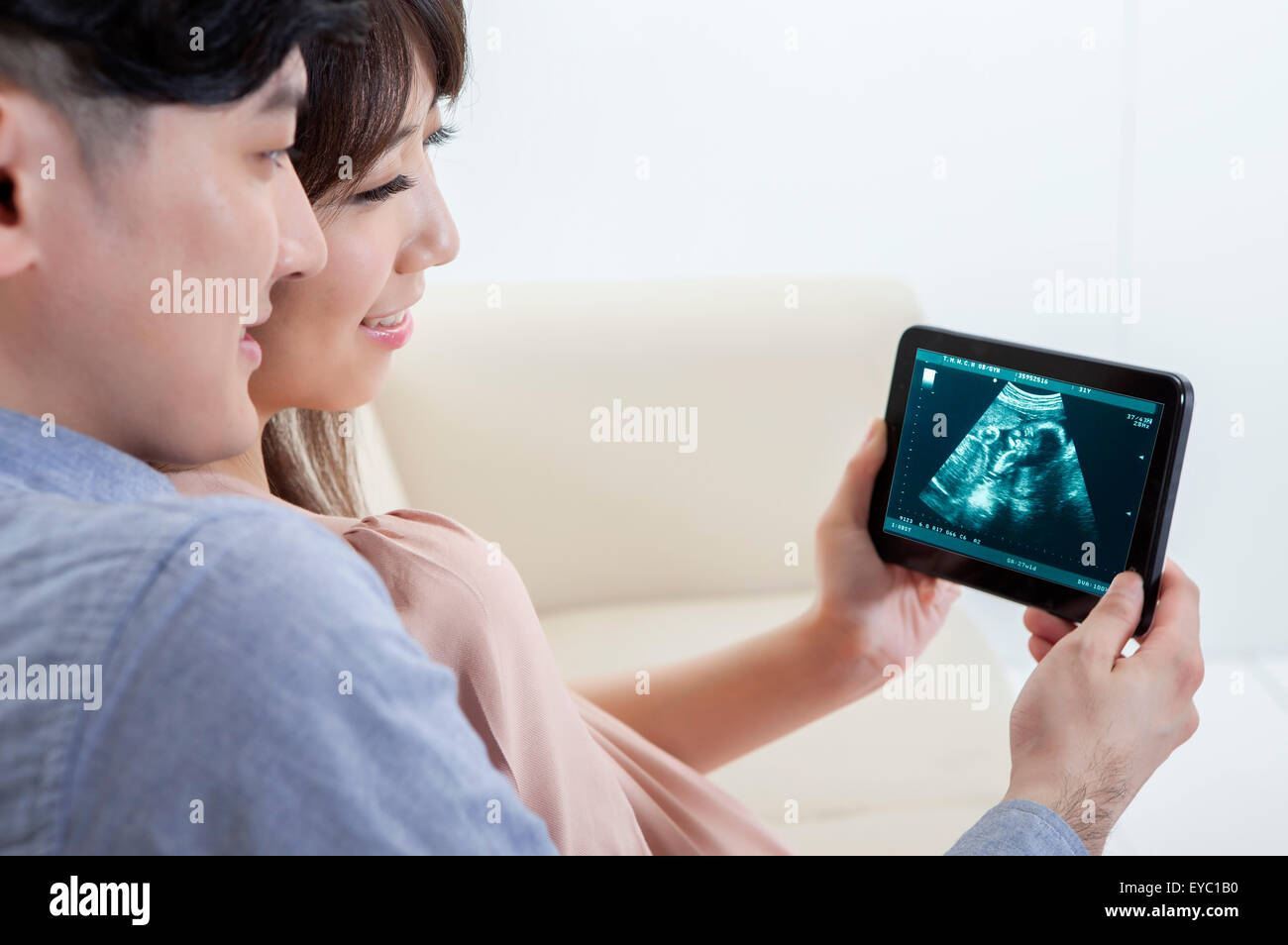 Jeune homme et femme enceinte tenant une tablette numérique, Banque D'Images