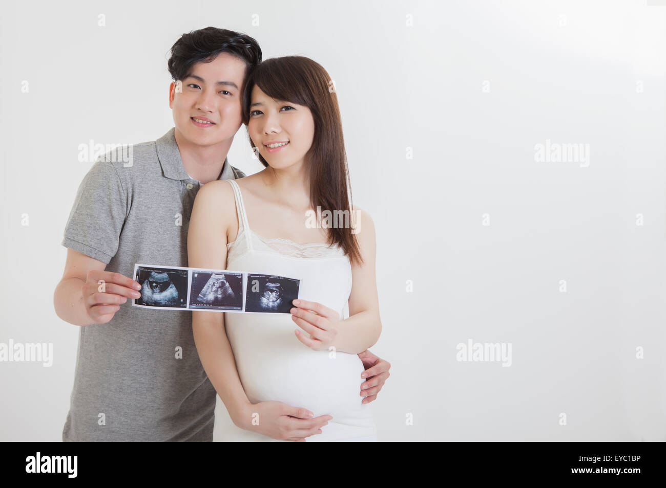 Jeune homme et femme enceinte tenant des photos avec le sourire, Banque D'Images