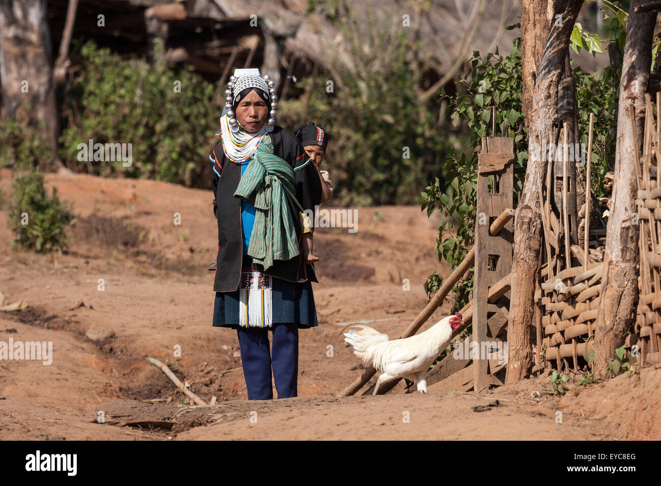 Femme de la région de la tribu Akha en vêtements typiques et des coiffures, portant un enfant sur son dos, Hokyin Village Akha Banque D'Images