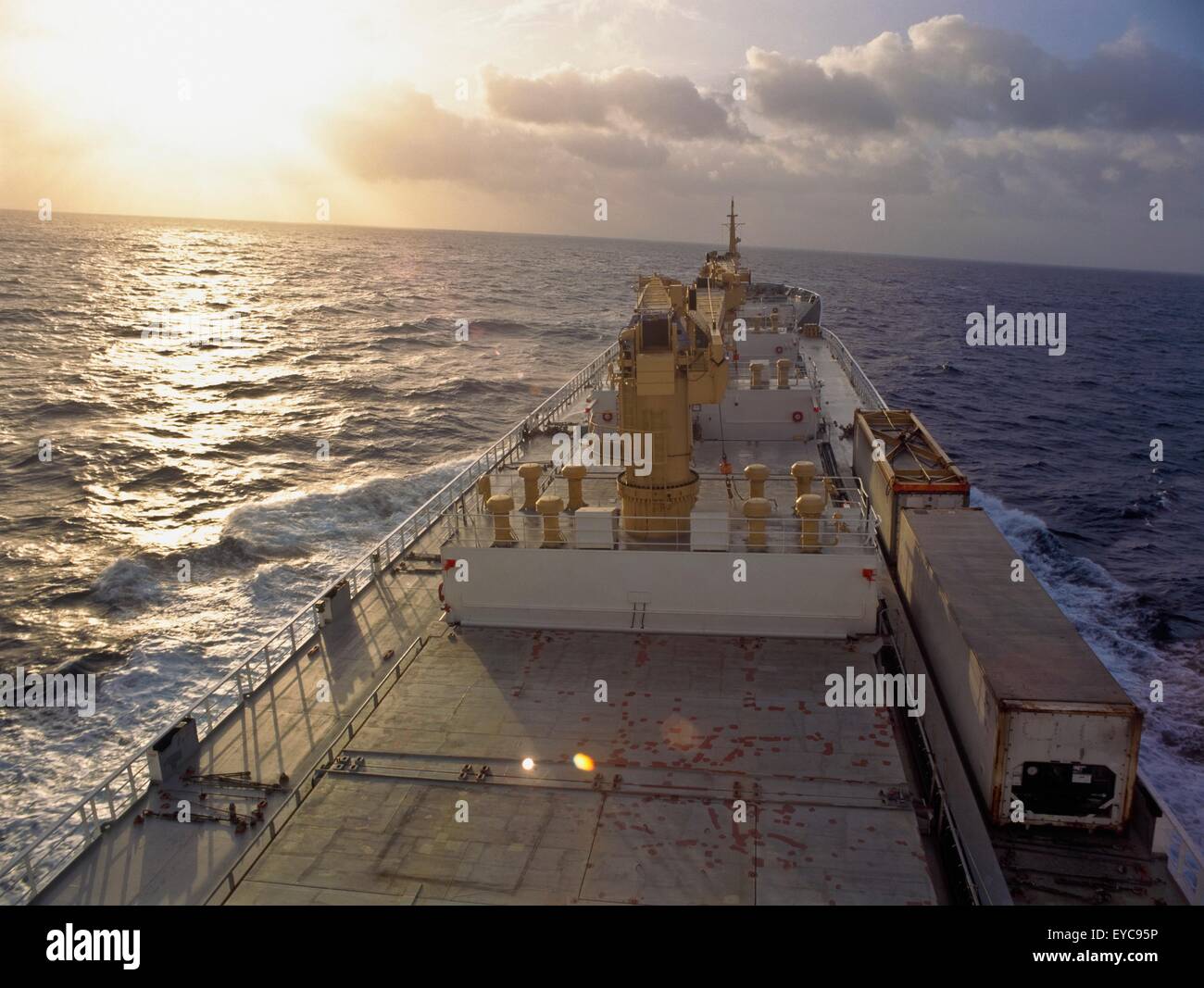 Porte-conteneurs ; Vue de l'eau d'un navire porte-conteneurs au coucher du soleil Banque D'Images