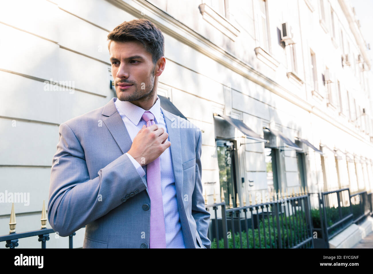Confident businessman redresse sa cravate en plein air Banque D'Images