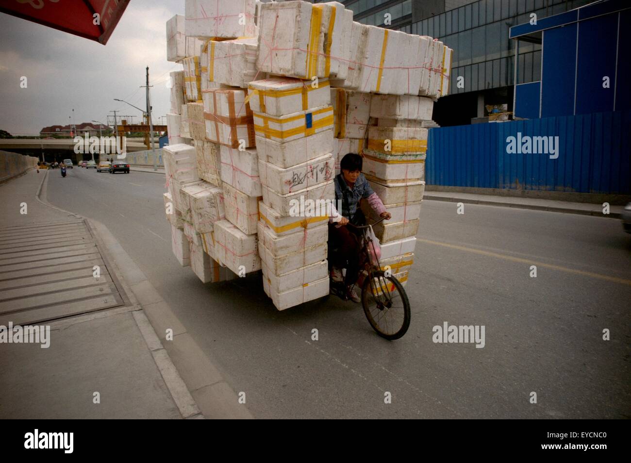 Un travailleur à Shanghai transporte une pile de boîtes en polystyrène sur un vélo. Banque D'Images