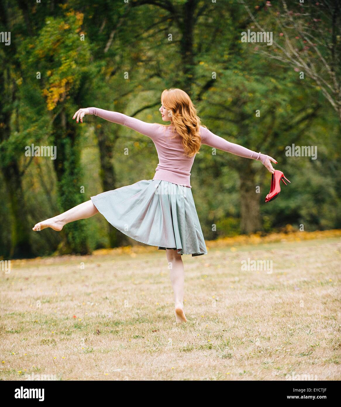 Vue arrière du jeune danseuse prête holding red High heels in park Banque D'Images