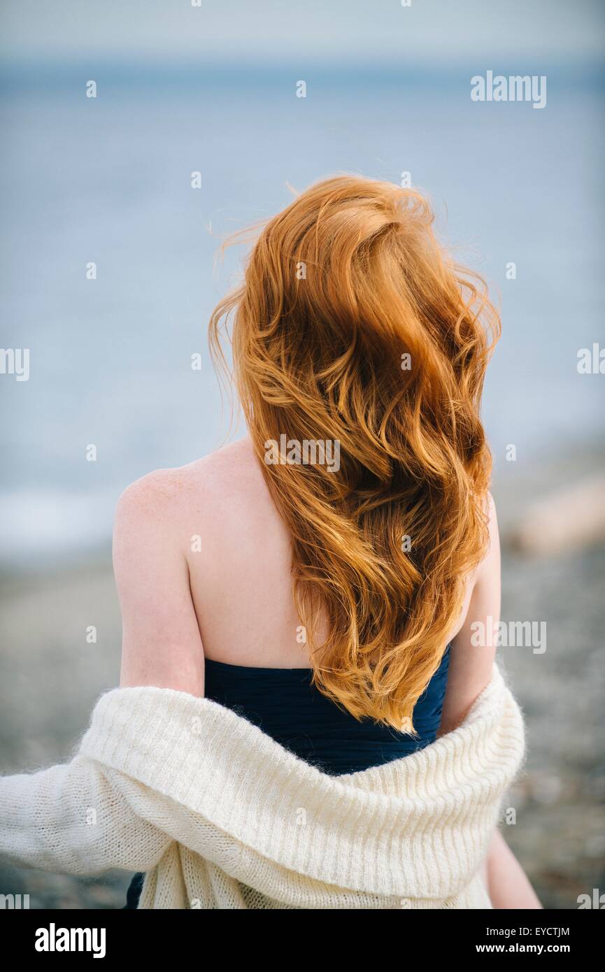 Vue arrière du jeune femme aux longs cheveux rouges surplombant la mer, Bainbridge Island, Washington State, USA Banque D'Images