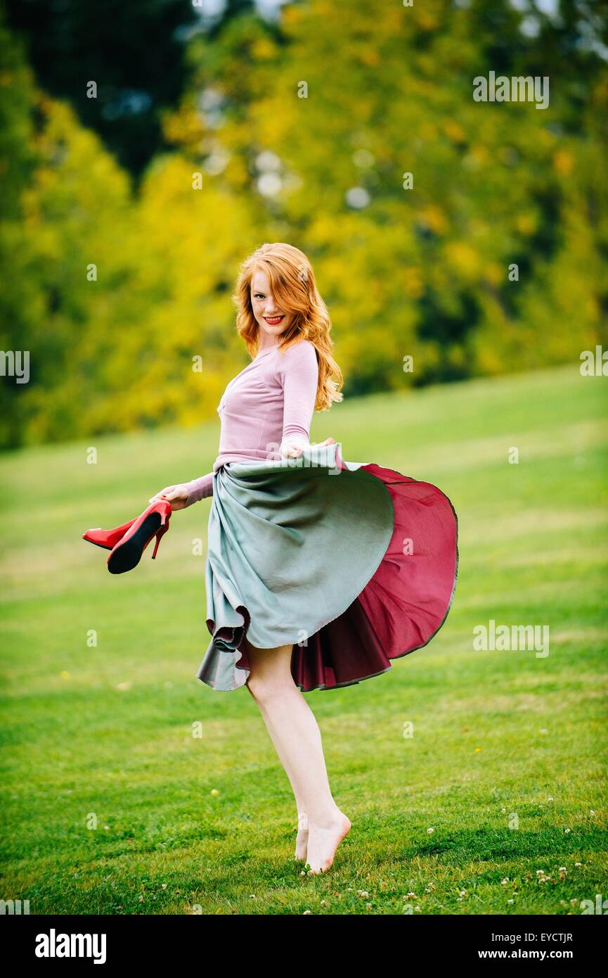 Portrait de jeune danseuse en équilibre et jupe portefeuille red High heels in park Banque D'Images