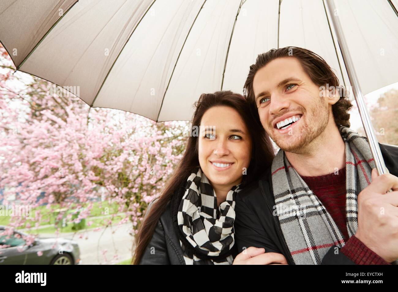 Jeune couple strolling in park with umbrella Banque D'Images