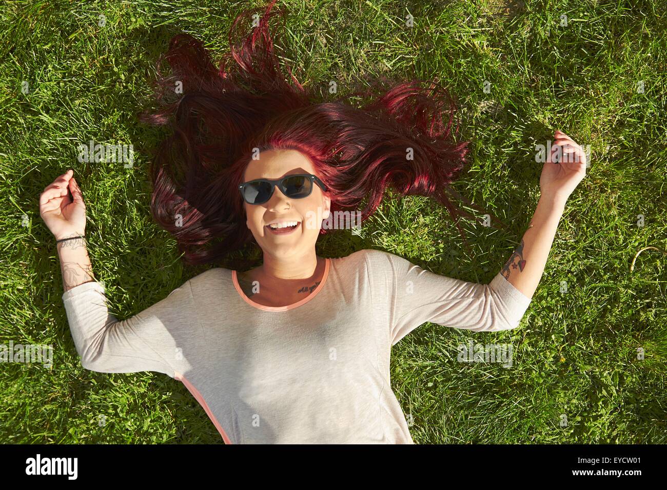 Vue de dessus de jeune femme aux cheveux rouges lying on grass Banque D'Images