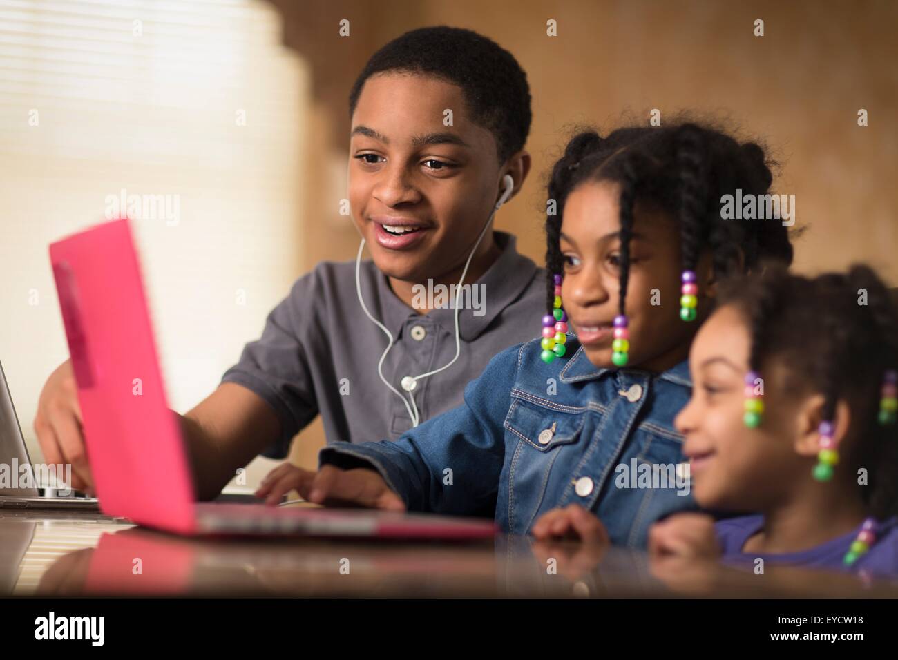 Adolescent et des soeurs à table à manger typing on laptop Banque D'Images