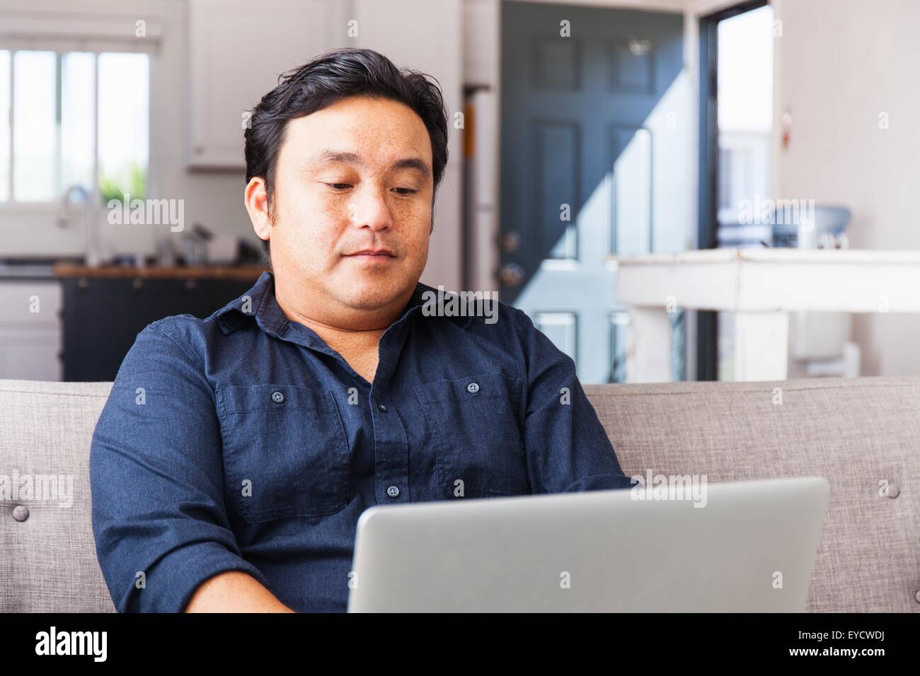 Man working on laptop on sofa Banque D'Images
