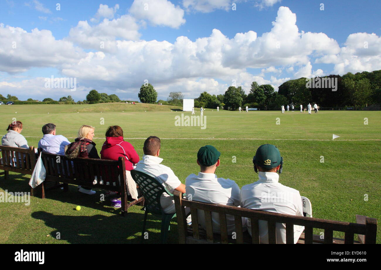 Cricketers watch theri coéquipiers rivaliser dans un match dans un village du Yorkshire près de Rotherham, Angleterre, Royaume-Uni Banque D'Images