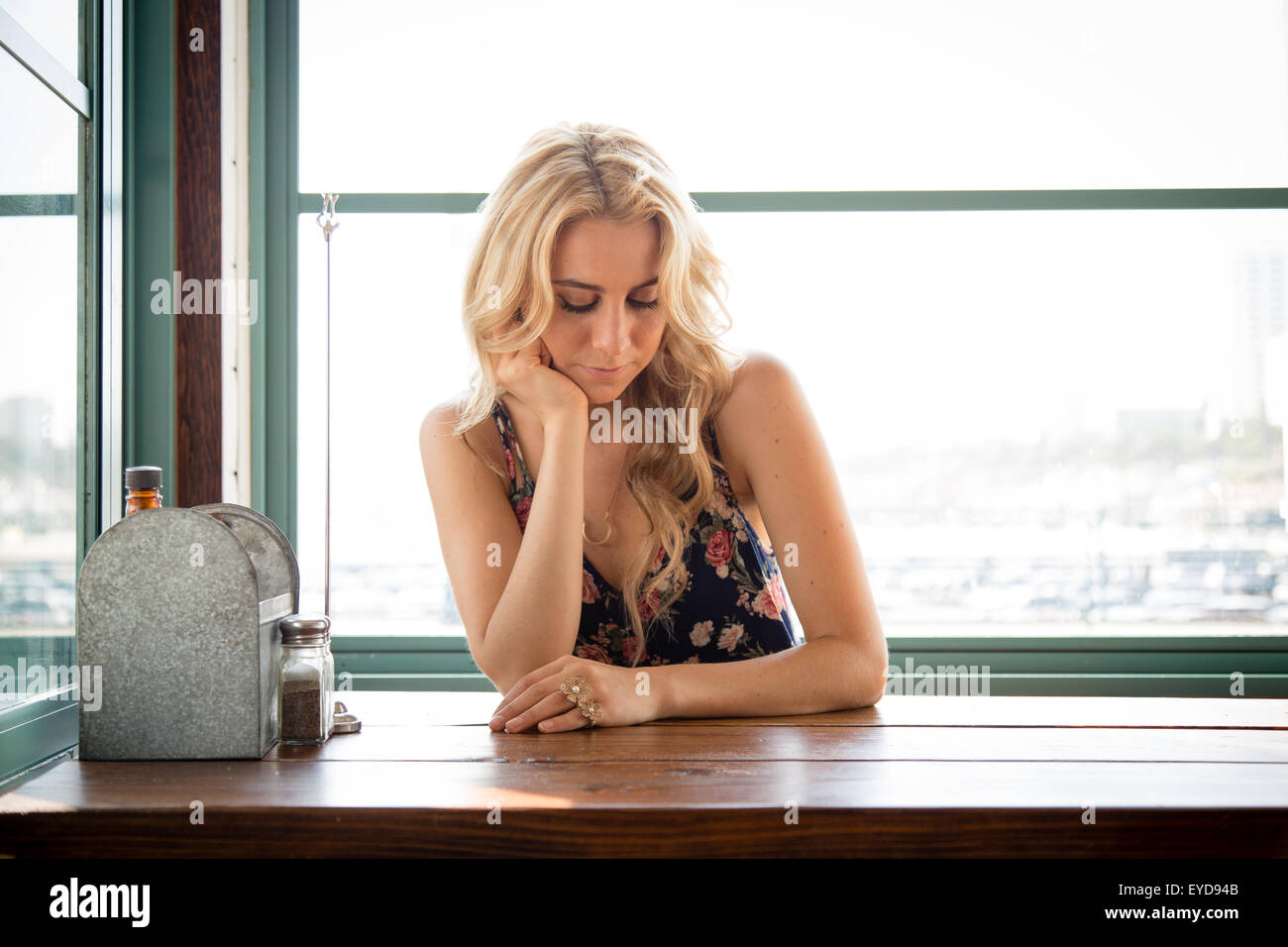 Une belle femme assise seule à une table dans un petit restaurant. Banque D'Images
