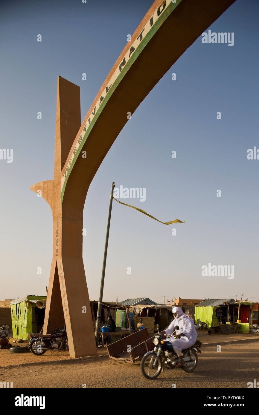 Le Niger, désert du Sahara, région d'Agadez, Touareg voilée riding bike crossing porte principale de la ville d'Agadez ; Banque D'Images