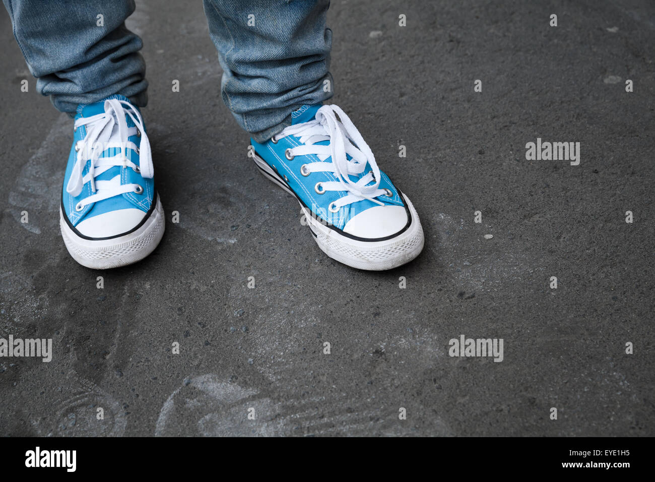 Espadrilles bleu, adolescent pieds de gumshoes position sur l'asphalte gris foncé. Photo Gros Plan avec mise au point sélective et peu profondes 6 Banque D'Images
