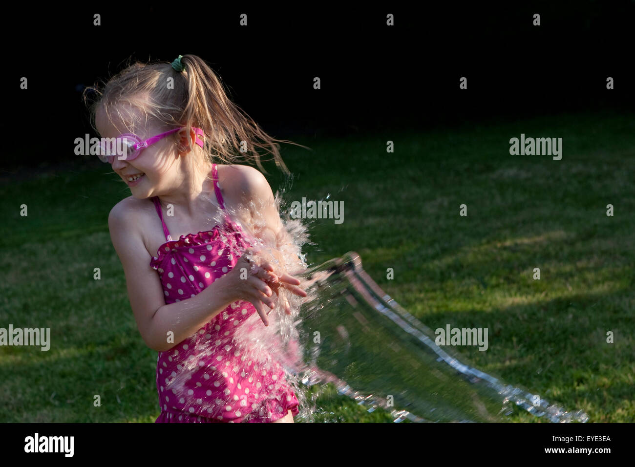 Fille jouant avec de l'eau dans le jardin en été. Banque D'Images