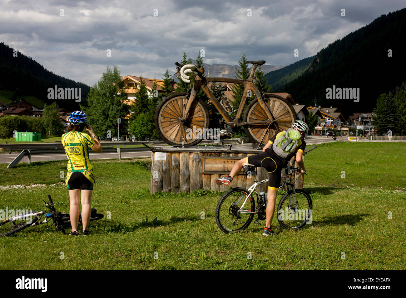 Les cyclistes reste d'une grande sculpture en bois vtt dans la ville de Corvara au cours de l'été saison de randonnée au Tyrol du sud. Banque D'Images