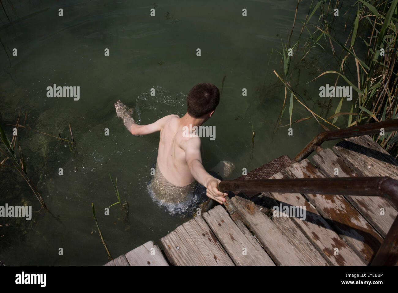 Un garçon de 17 ans entre dans un lac d'eau douce en Kaltern-Caldaro, Tyrol du sud, Italie du nord. Banque D'Images