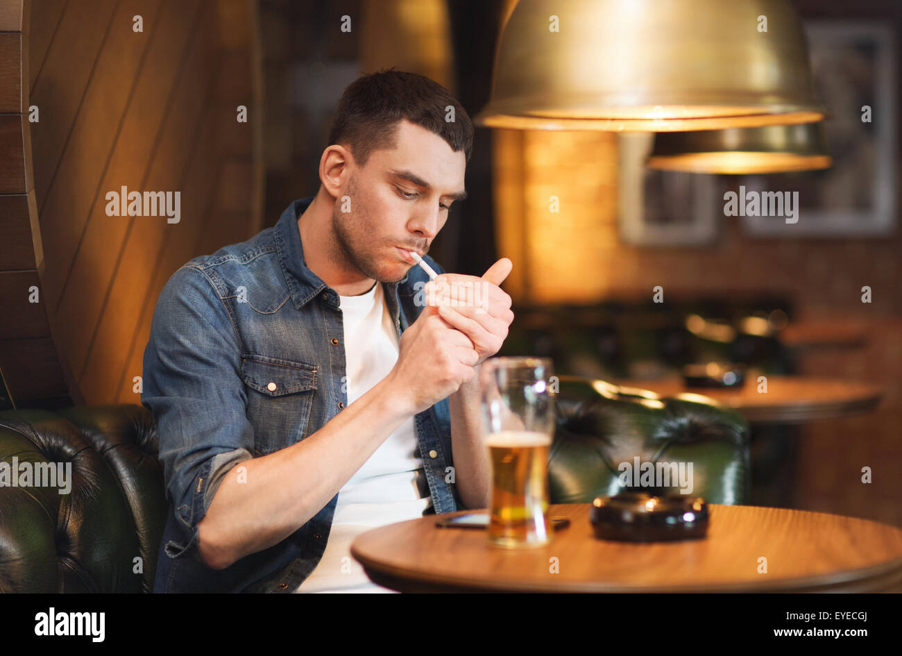 L'homme de boire une bière et fumer cigarette à bar Banque D'Images