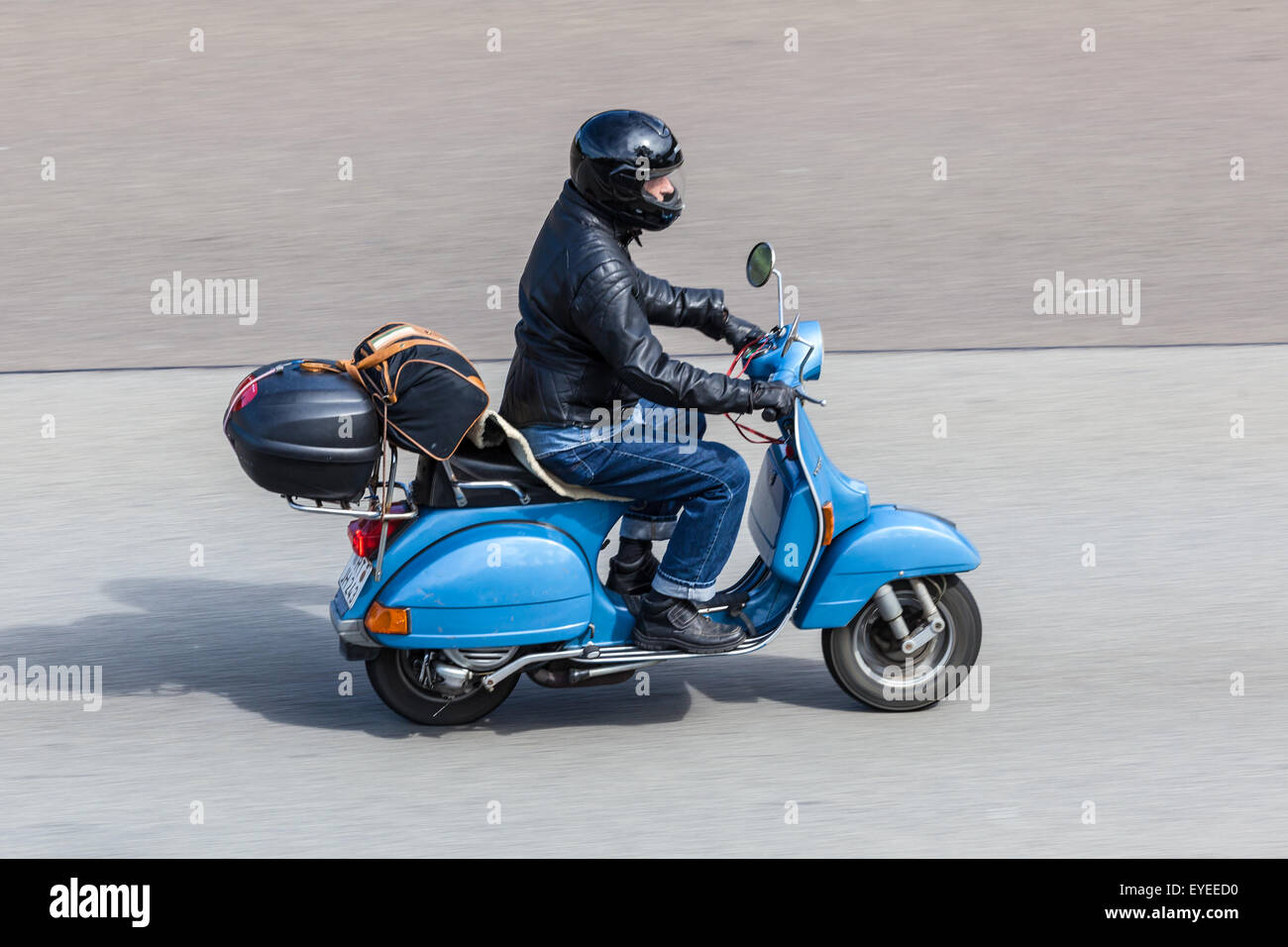 Scooter Vespa bleu se déplacer rapidement sur la route goudronnée Banque D'Images