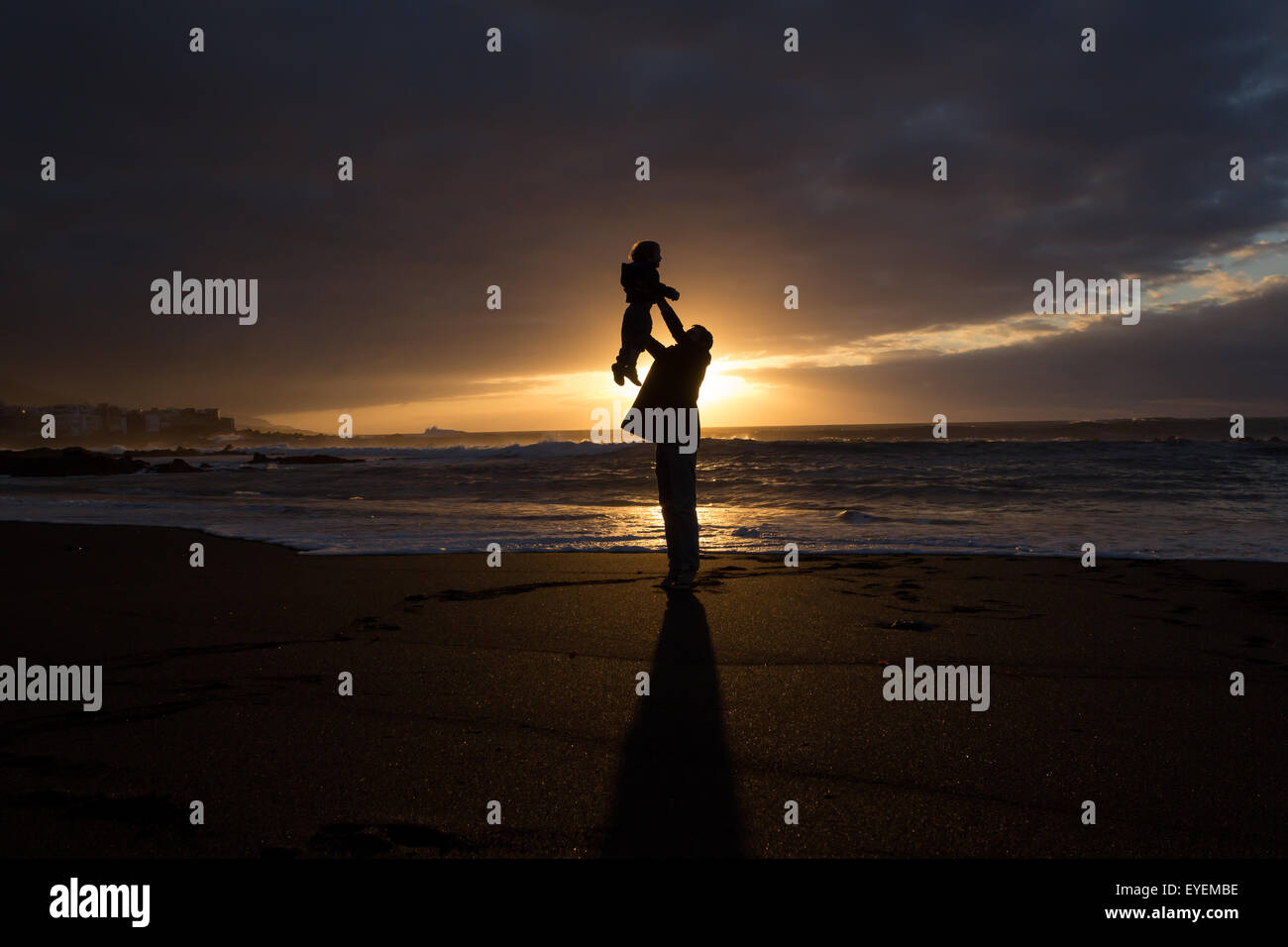 Père tenant un enfant dans l'air . famille heureuse silhouette, beach sunset Banque D'Images
