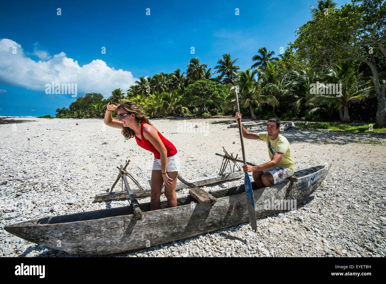 Les touristes jouant dans un bateau en bois sur la plage ; l'île de Tanna, Vanuatu Banque D'Images
