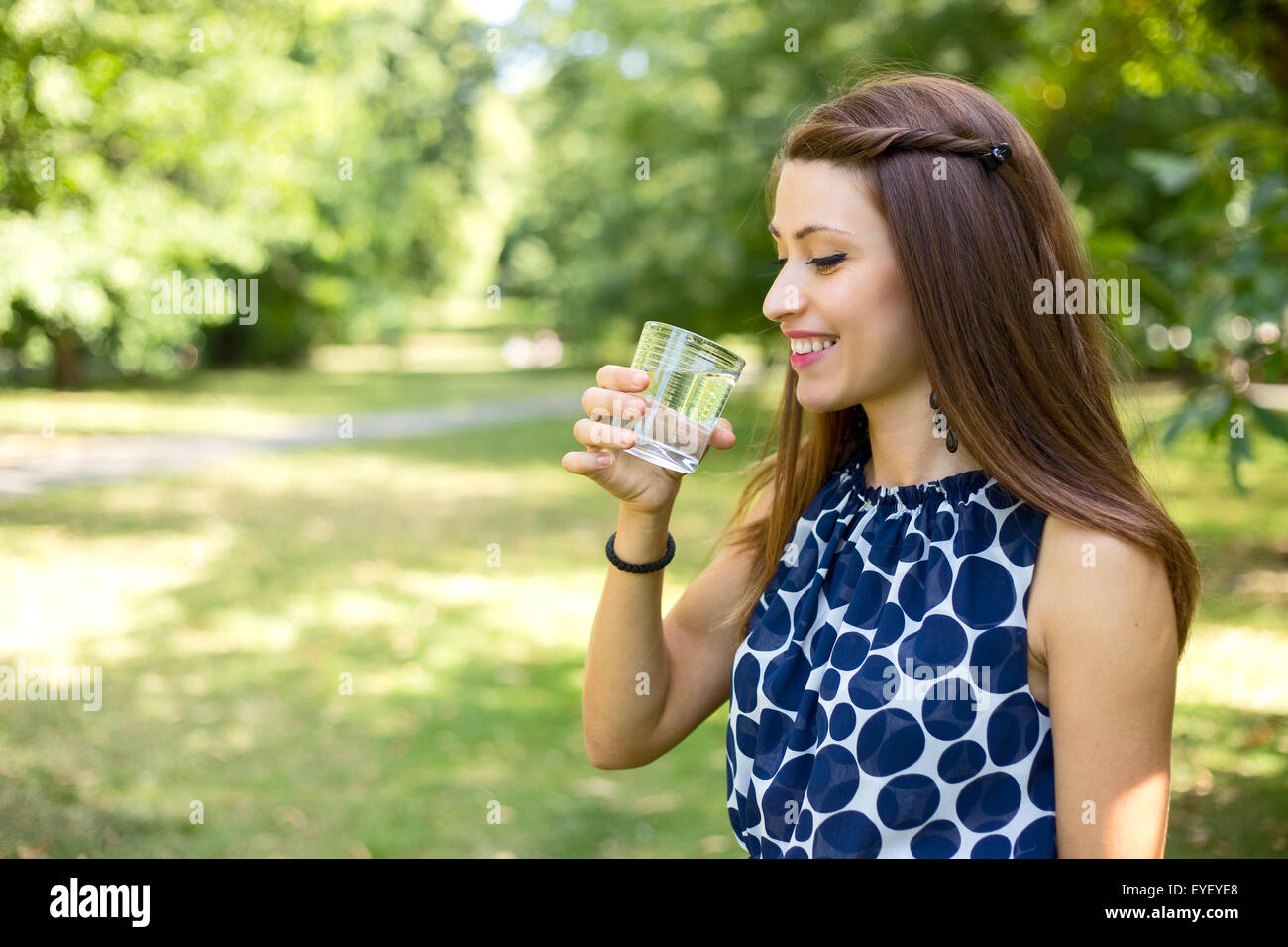 Jeune femme à boire un verre d'eau à l'extérieur Banque D'Images
