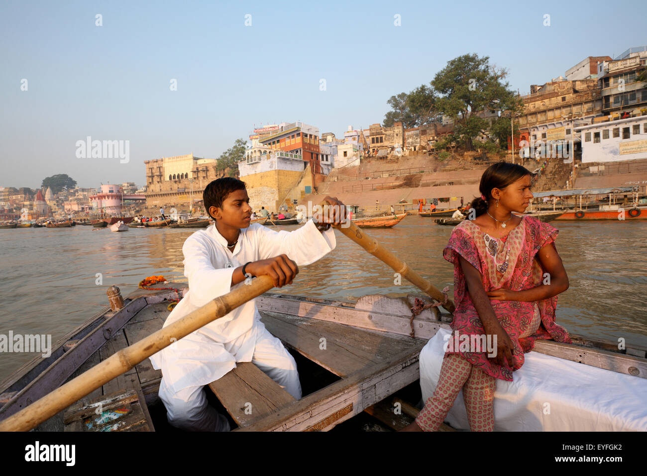 Un couple d'un bateau d'aviron dans le Gange passé l'echelle ghats ; Varanasi, Inde Banque D'Images