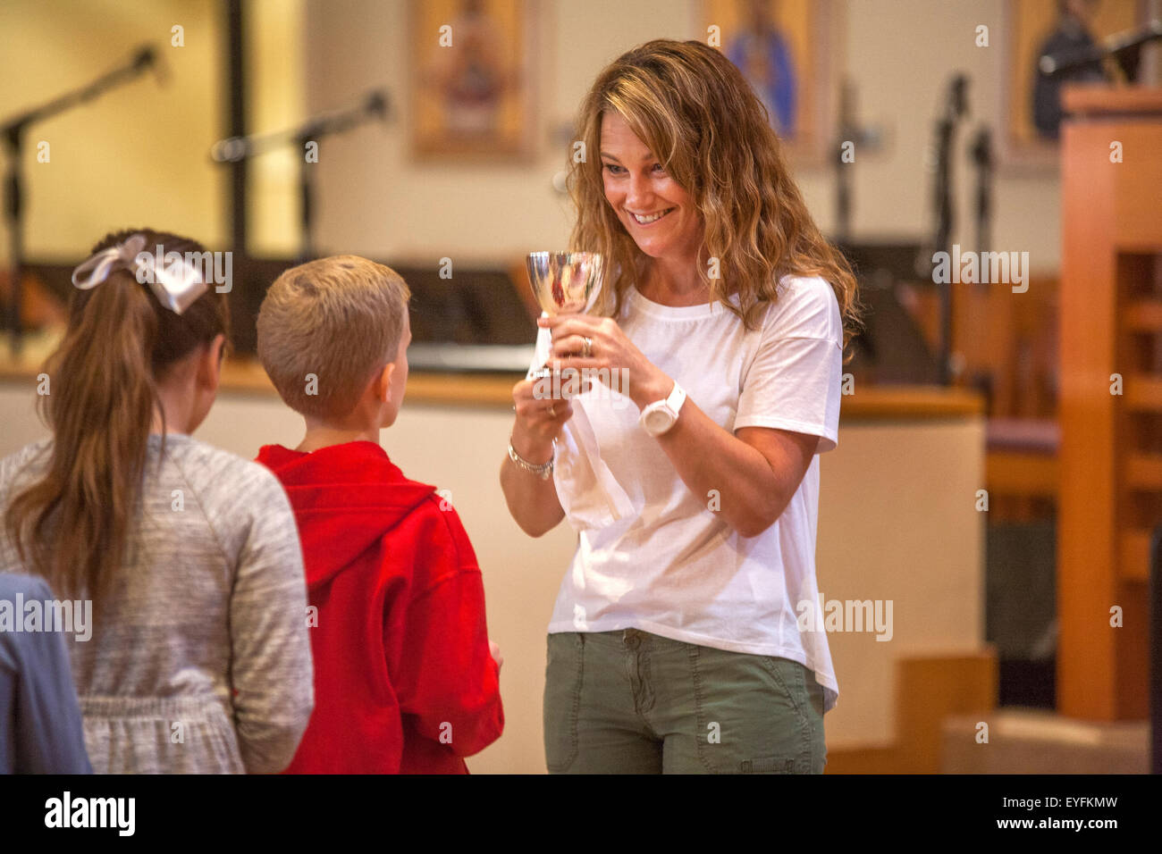 Lors d'une Laguna Niguel, CA, l'église catholique un bénévole des femmes démontre la réception de la communion à l'enfant de vin multiraciale paroissiens en préparation de leur première communion, également connu sous le nom de la Sainte Eucharistie. Banque D'Images