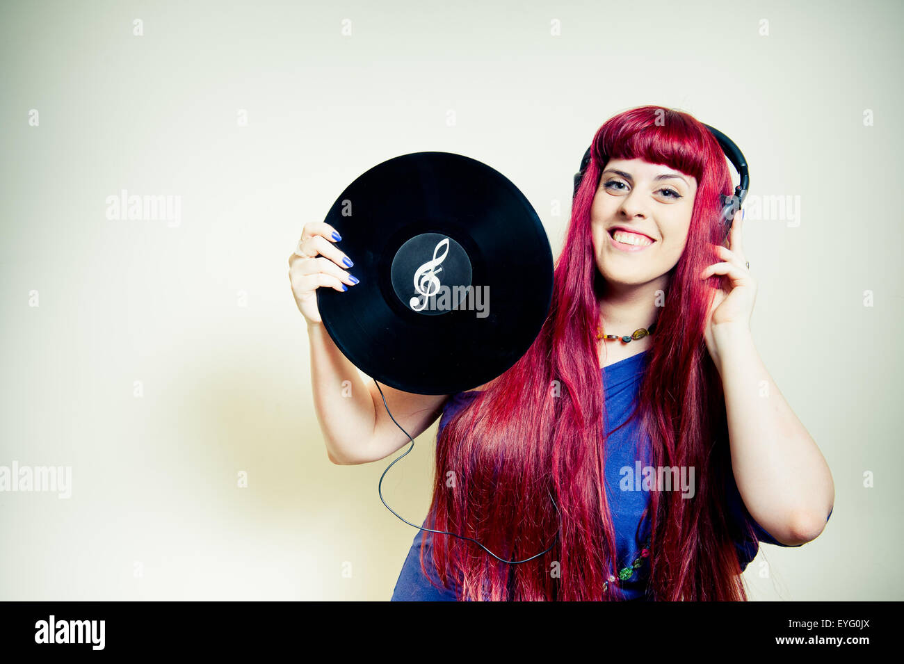 Jolie jeune femme dansant avec un casque et d'un disque vinyle avec symbole clef de sol Banque D'Images