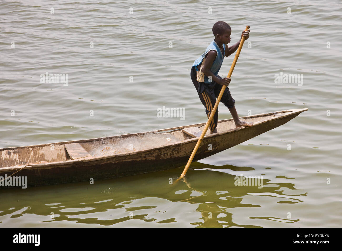 Au Niger, les pêcheurs Hausa garçon descendant sur le fleuve Niger en pirogue traditionnelle ; Niamey Banque D'Images
