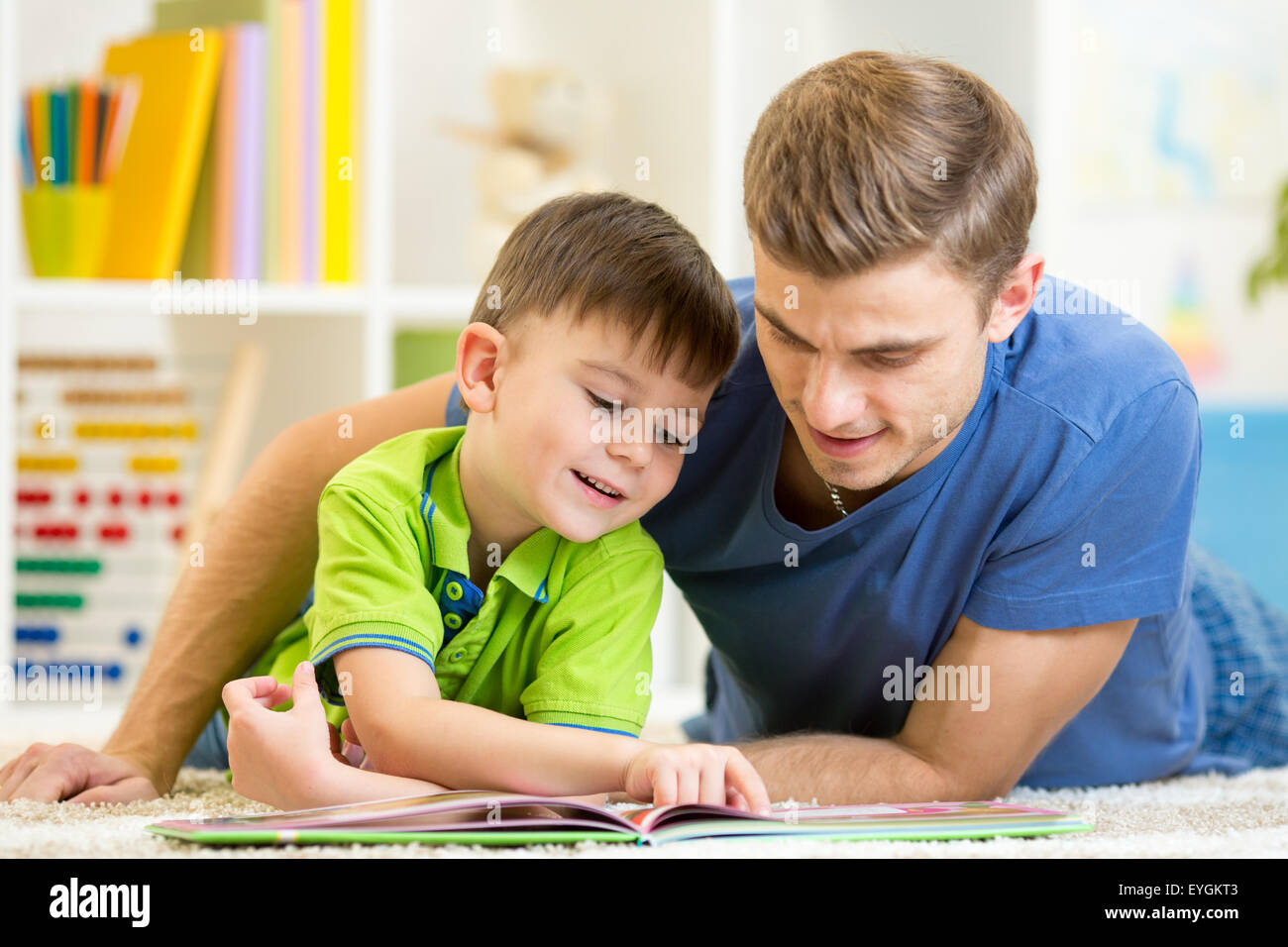 Père et fils lire ensemble assis sur le plancher. Lecture pour enfants livre d'histoires avec son père à la maison. Banque D'Images