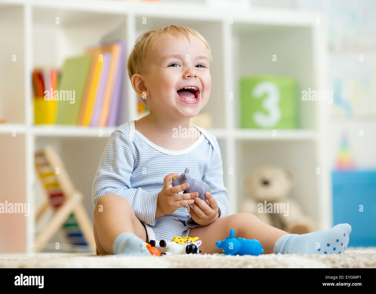 Heureux petit garçon. Smiling enfant joue les jouets des animaux à la maison ou au jardin. Banque D'Images