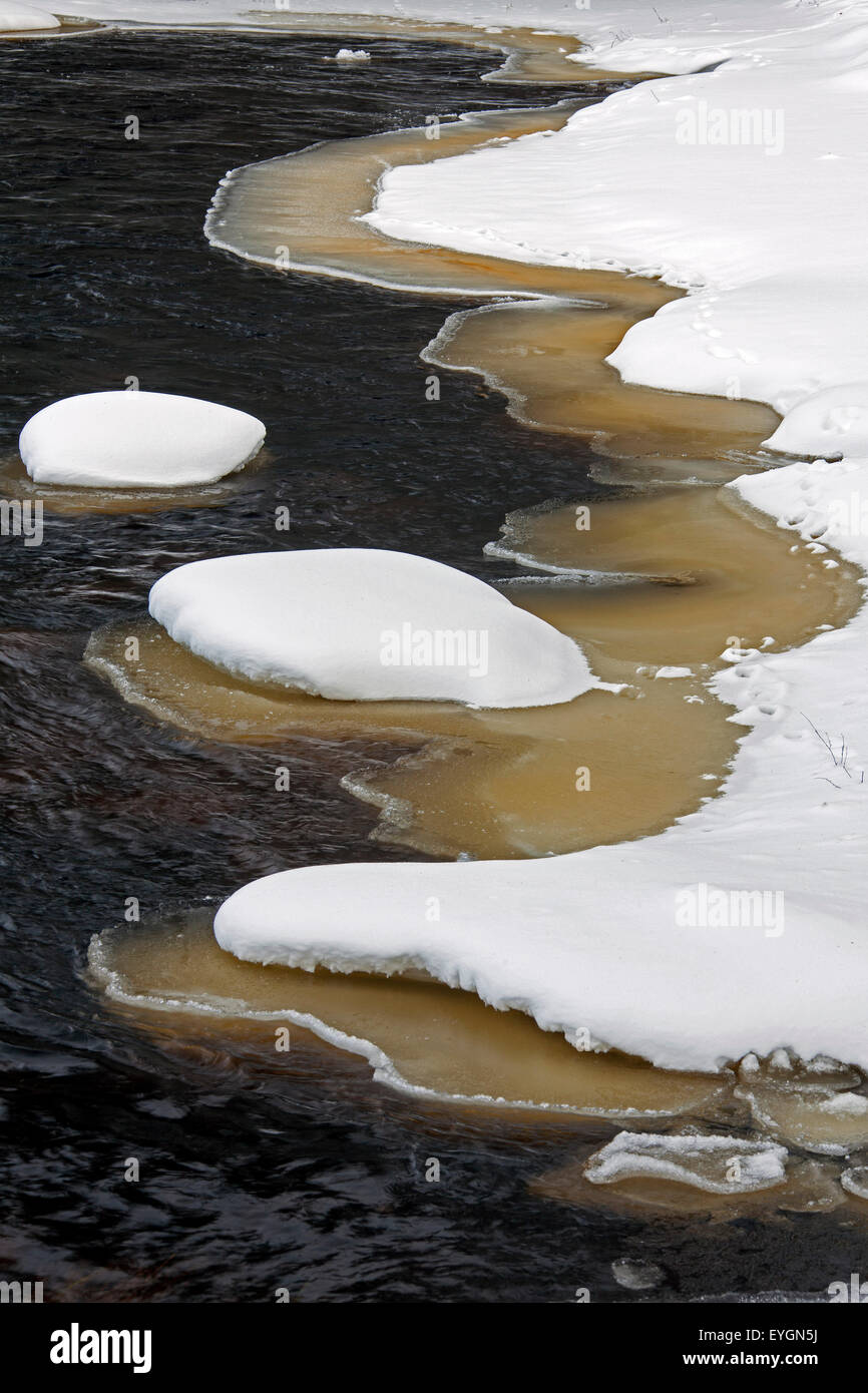 Brown slush ice le long de rivière recouvert de neige en hiver Banque D'Images