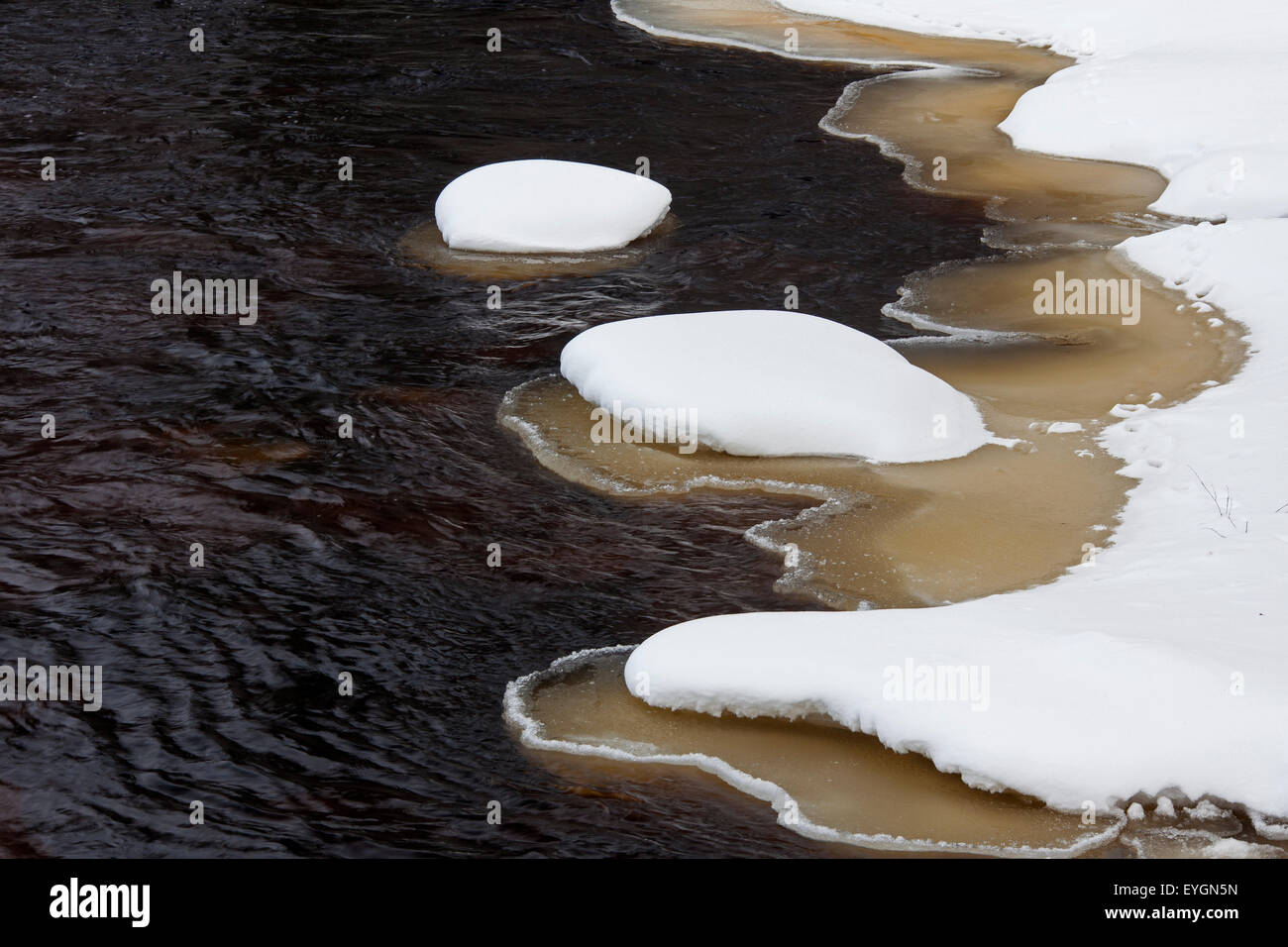 Brown slush ice le long de rivière recouvert de neige en hiver Banque D'Images